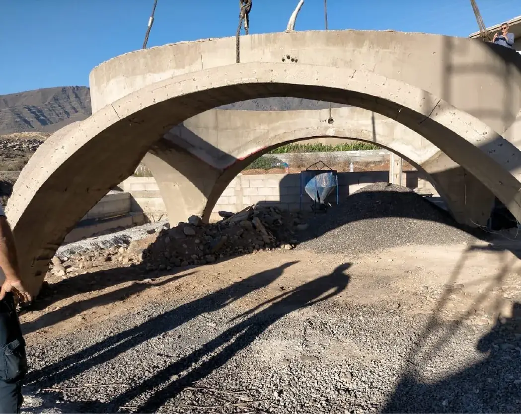 Gran arco de hormigón suspendido con eslingas en una obra.